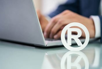 Registered trademark emblem next to laptop