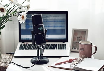 Recording a podcast with a microphone and laptop on desk